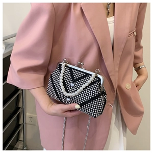 Detail of black rhinestone handbag with pearl handle and heart decor on pink blazer