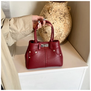 Detail der weinroten PU-Handtasche mit Lychee-Struktur und silbernem Metall-Drehverschluss