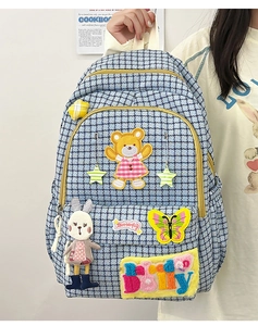 Detailed view of the blue plaid nylon backpack with cartoon patches and rabbit pendant
