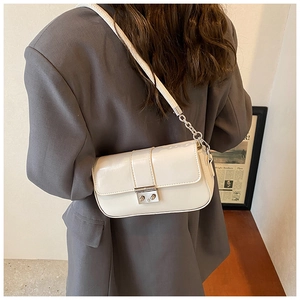 Crossbody cream PU leather bag with glossy finish and silver buckle on a gray blazer model