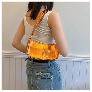 Détail du sac baguette orange-doré métallisé avec bandoulière à rivets et fini brillant