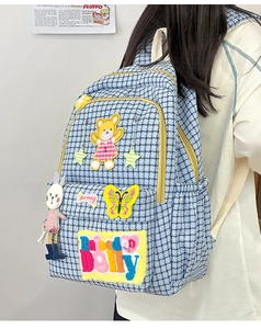 Detail of blue plaid nylon backpack with cute bear embroidery and rabbit keychain