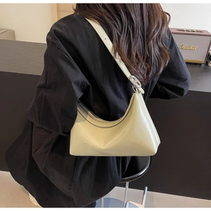 Detail of light green PU leather half-moon bag with round silver buckle and metal accents