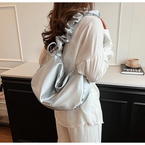 Detail of silver metallic dumpling bag featuring ruffled shoulder strap and ruched PU fabric