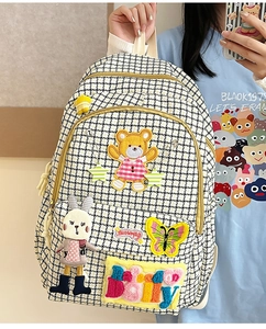 Detail of black and white checkered backpack featuring cute bear and rabbit patches