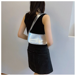 Sac à bandoulière argenté Y2K avec œillets métalliques porté par un mannequin en détail