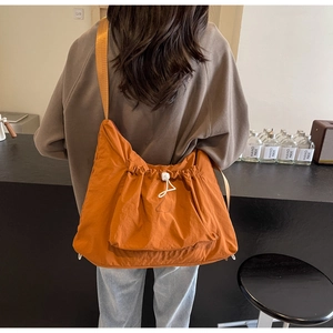 Detailed view of casual orange crossbody bag with drawstring design and wide strap