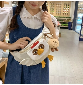 Détail du sac bandoulière poussin blanc en nylon avec porte-clés ours brun sur mannequin