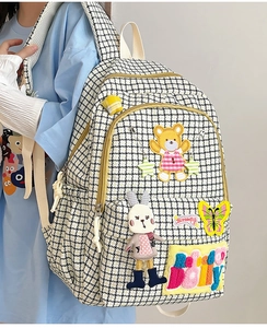 Detail of trendy houndstooth backpack with cartoon patches and plush doll ornaments