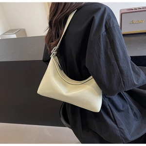 Detail of minimalist pale yellow faux leather underarm bag on model in black dress