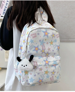 Close-up of nylon backpack with colorful star prints and a white puppy plush pendant