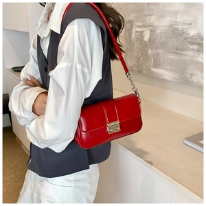Detail of red patent leather shoulder bag with silver metallic buckle and chain strap