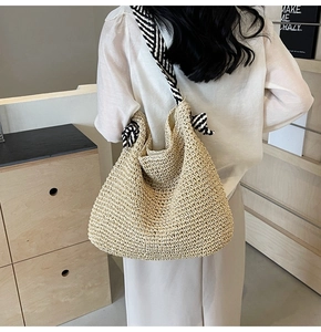 Détail d'un sac bandoulière en paille beige avec tissage et sangle rayée