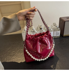 Detailed macro of burgundy pleated bucket bag with pearl chain and silver stud accents