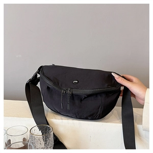 Detail of black crescent crossbody bag showing washed nylon fabric and double zippers