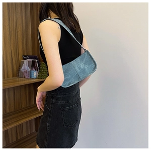 Vue latérale du sac punk bleu avec bandoulière à rivets argentés porté par un mannequin