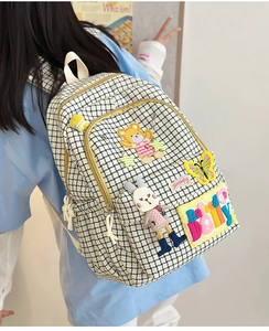 Close-up of beige plaid nylon backpack with cartoon plush patches and BOLLY lettering