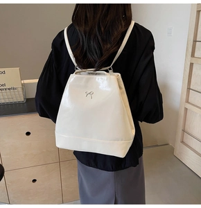 Back view of model wearing a glossy beige PU backpack with silver bow hardware detail