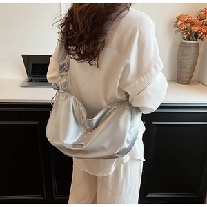 Silver crescent moon shoulder bag with soft metallic finish shown on model's shoulder