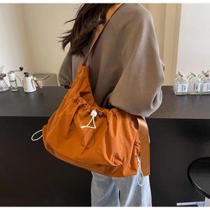 Detail of caramel orange nylon drawstring crossbody bag with wide shoulder strap