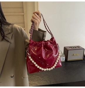 Detailed macro of burgundy bucket bag with quilted texture and pearl chain strap