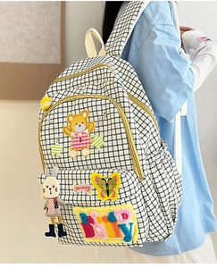 Detail of nylon backpack with houndstooth pattern, colorful patches, and a cute rabbit charm