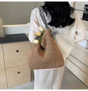 Détail de la texture d'un sac en paille marron avec bandoulière à rayures noires et blanches