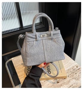 Détail du sac bandoulière en denim bleu clair avec fermoir rotatif argenté et rivets