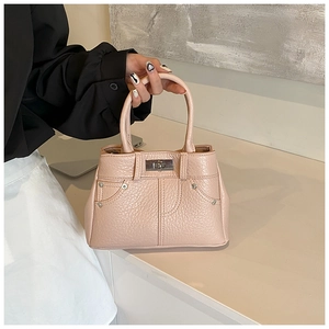 Detailansicht der PU-Lederhandtasche in Nuderosa mit Lychee-Struktur, Drehverschluss und Nieten