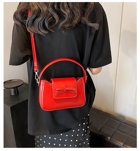 Detailed close-up of a red PU leather handbag with a 3D bow accent and textured finish