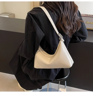 Side view of cream half-moon PU leather underarm bag with adjustable strap and metal ring