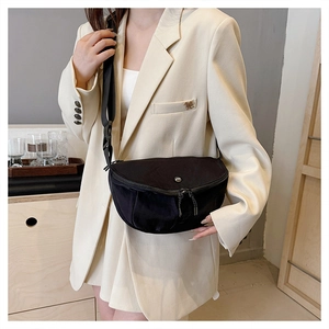 Detailed view of a black crescent crossbody bag worn over a beige blazer with wide strap