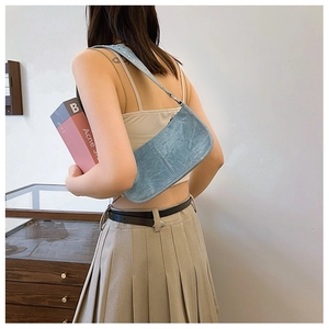 Détail des rivets argentés sur la bandoulière en denim bleu clair portée par le mannequin