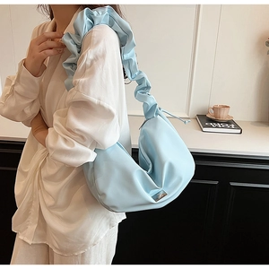 Detail of light blue pleated PU hobo bag featuring wide ruched strap and metal plaque