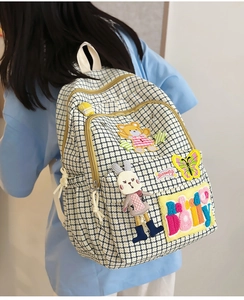 Detail of checkered nylon backpack featuring cute bear embroidery and 3D plush rabbit doll