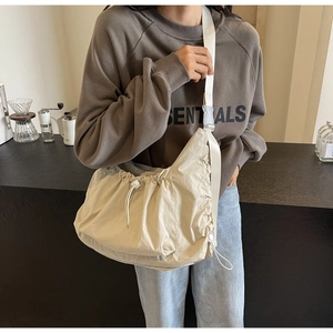 Detail view of stylish beige crescent crossbody bag with drawstring pleated design