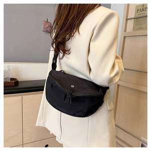 Side view of black washed fabric crossbody bag with adjustable strap and metal zippers
