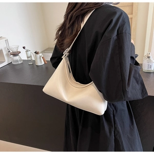 Detailed view of cream PU leather hobo bag worn by model in a minimalist cafe setting