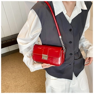 Detail of red PU leather crossbody bag with silver metal buckle and chain strap