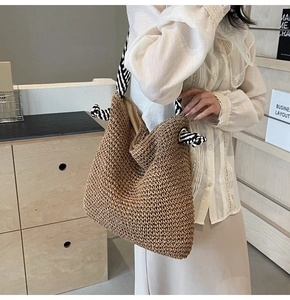 Détail d'un grand sac cabas en paille tressée avec bandoulière en corde rayée bicolore