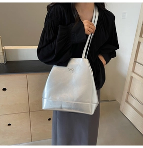 Detail of silver metallic shoulder bag with delicate bow ornament and slim strap