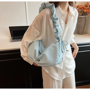 Detail of light blue pleated shoulder bag with ruffle strap and metallic logo plate