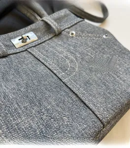 Détail macro de la texture denim bleu et du fermoir tournant en métal argenté