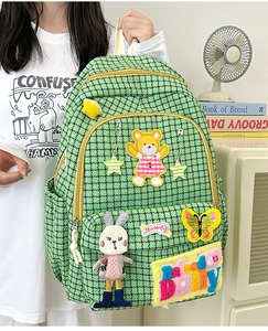 Close-up of green houndstooth nylon backpack featuring embroidered cartoon animal patches