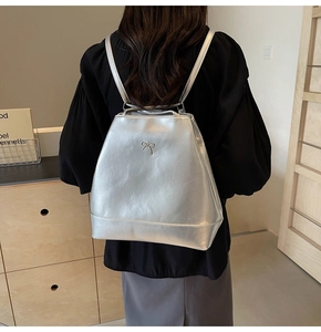 Silver PU leather backpack for women featuring a metal bow detail and thin shoulder straps