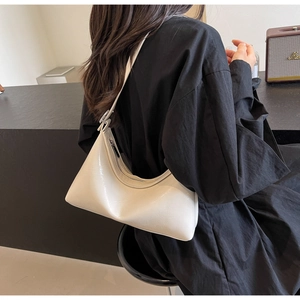Detail of a beige PU leather hobo bag worn by a model, showing sleek glossy finish