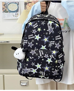 Close-up of black nylon backpack with star pattern and cute white puppy plush keychain