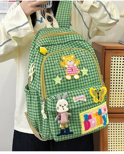 Detailed close-up of green checkered backpack featuring cute 3D cartoon animal embroidery