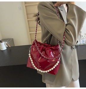 Detail of red quilted bucket bag with pearl handle and silver chain strap for women