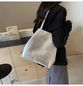 Detail of silver tote bag with metallic bow logo and long shoulder strap for women